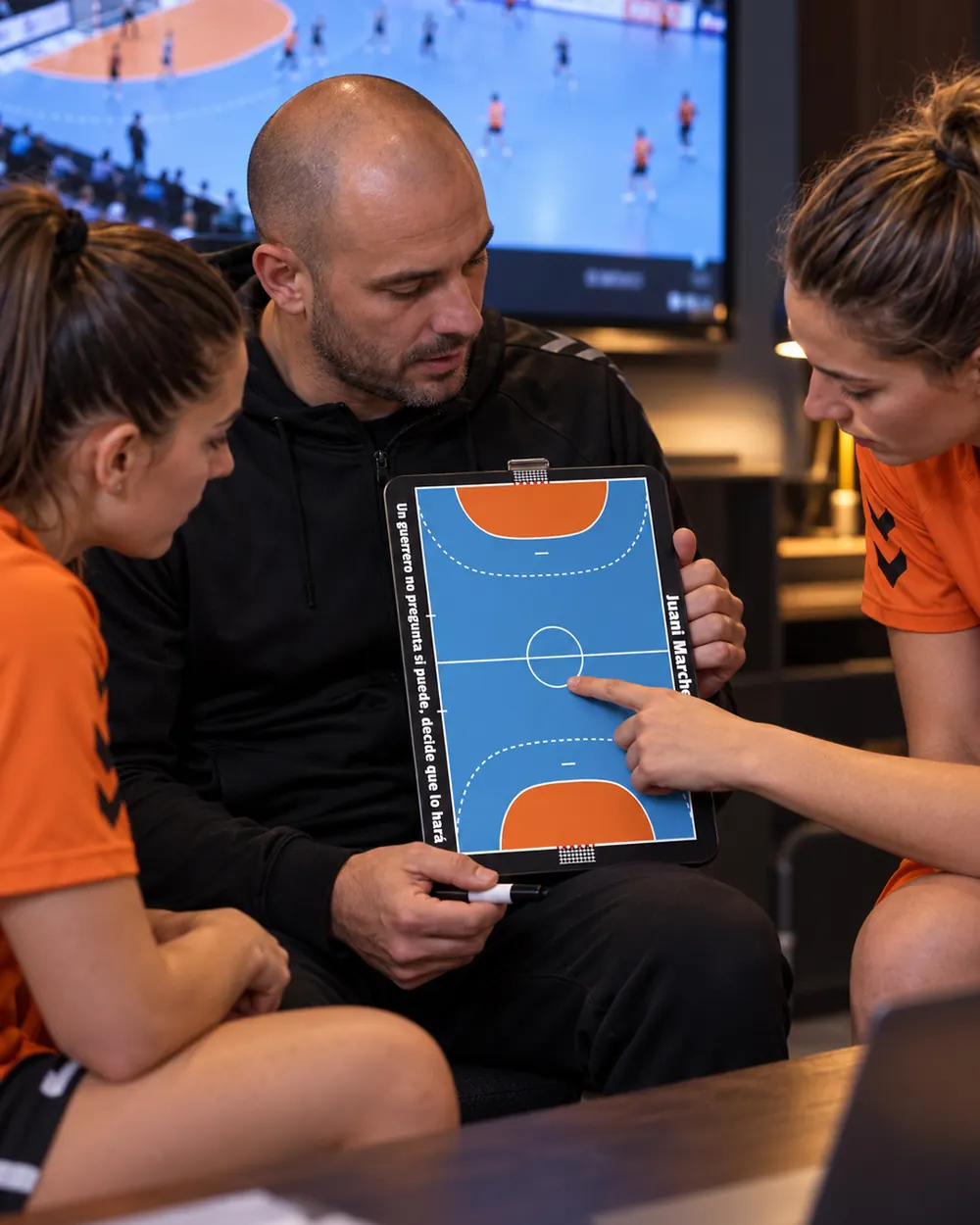 A handball coach goes over tactics on the whiteboard with his players